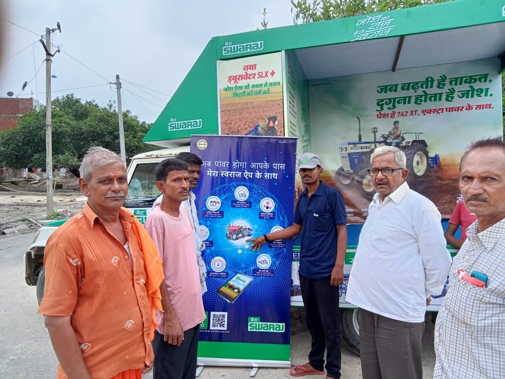 Promoters talking to customers beside a Swaraj van and standee